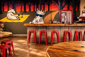 A bar area with red stools, a wooden counter, and a mural of wolves.
