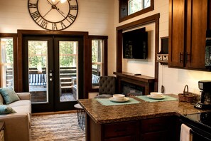 A kitchen with a large clock, wooden cabinets, a fireplace, and a dining area with a view of the outdoors. - Glorious Cabin with Stunning Sights in Monteagle, Tennessee (Monteagle)