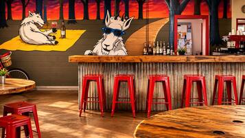 Zona de bar con taburetes rojos, una barra de madera y un mural de lobos.