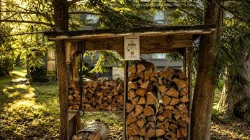 Une structure en bois, agrémentée d’une enseigne, entourée d’arbres et bordée d’une pile de troncs d’arbres.