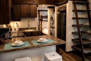 A kitchen with a built-in washer and dryer, a coffee maker, and a wooden ladder. - Glorious Cabin with Stunning Sights in Monteagle, Tennessee (Monteagle)