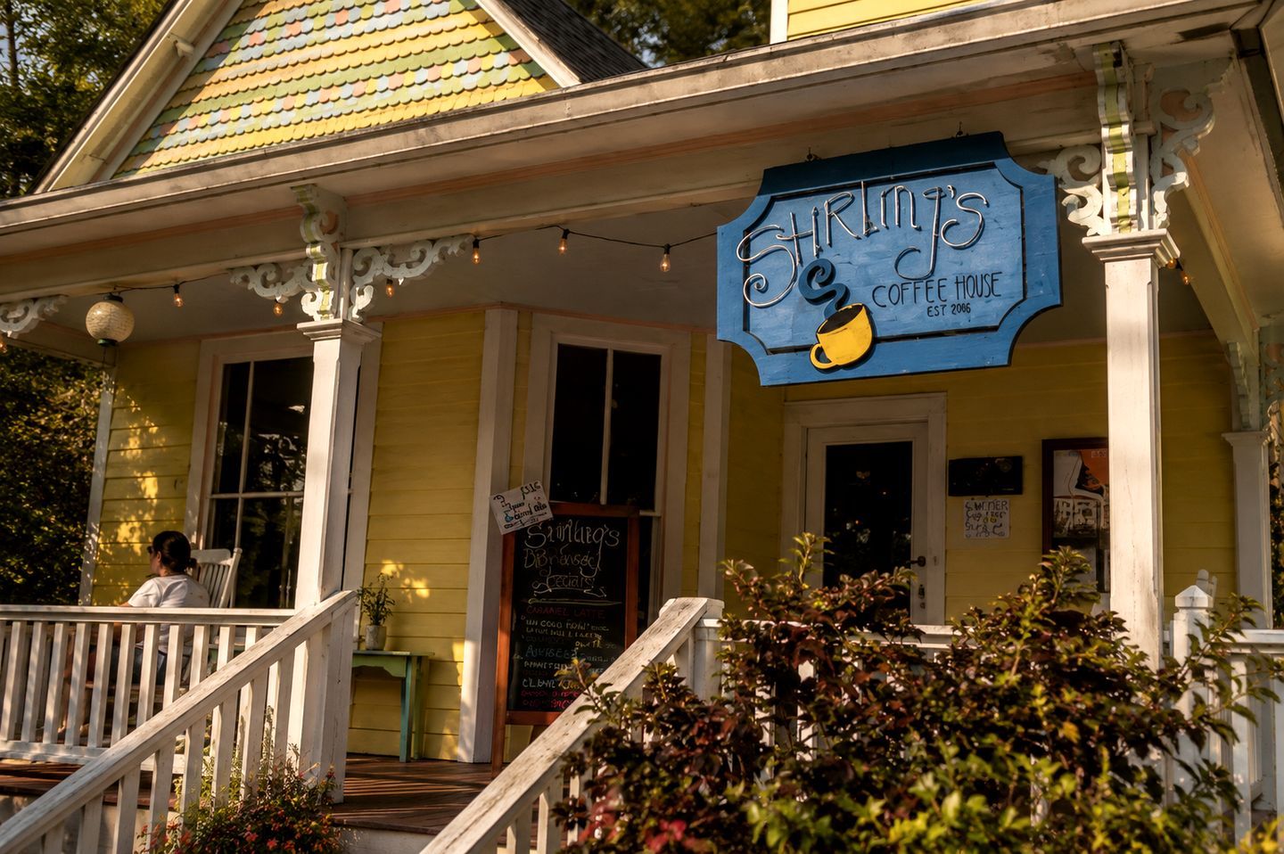 A yellow building with a blue sign reading 'Shrimp's Coffee House' and a staircase leading to the entrance.
