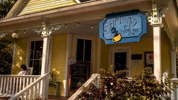 A yellow building with a blue sign reading 'Shrimp's Coffee House' and a staircase leading to the entrance.
