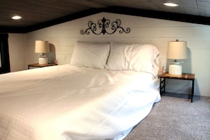 A bedroom with a large bed, two bedside tables with lamps, a decorative wall headboard, and a carpeted floor. - Glorious Cabin with Stunning Sights in Monteagle, Tennessee (Monteagle)
