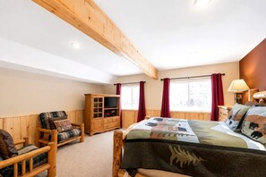 Ein Schlafzimmer mit einem hölzernen Bett, einem Fernseher, einem Holzschrank und einem Fenster mit Vorhängen.