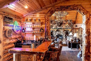 Un intérieur rustique avec un coin bar, des murs en bois et une cheminée en pierre.