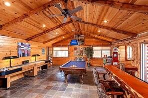 Ein Holzinterieur mit Billardtisch, Bar und Deckenventilator.