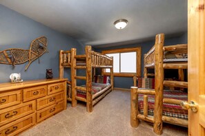 Een kamer met stapelbedden, een dressoir en een raam.