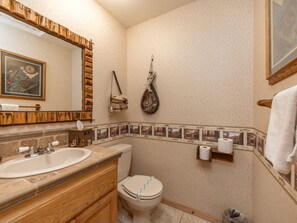 Een badkamer met een houten wastafelmeubel, een wastafel, een toilet en een handdoekhouder.