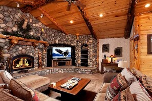 Un intérieur chaleureux et accueillant, avec une cheminée en pierre, un téléviseur et un coin salon confortable.