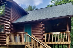 A log cabin with a balcony, a green door, and a sign indicating 'Hideaway Cabin.' - Rural Quaint Cabin with Large Private Deck and Hammock in Arkansas (Eureka Springs)