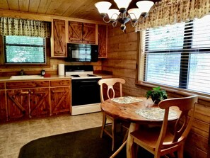 A wooden cabin kitchen with a stove, microwave, and wooden cabinets. - Group 4) The Hideaway (Eureka Springs)