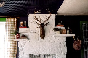 A fireplace with a mounted deer head, surrounded by shelves with books, a lantern, and decorative items. - Family Glampsite: A Unique Cabin Retreat for Adventure in Tracy City, TN (Tracy City)