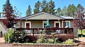 A single-story building with a covered porch, a small garden area, and a clear sky.