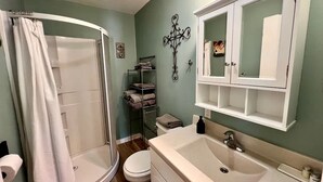 A bathroom with a shower, toilet, sink, and towel rack.
