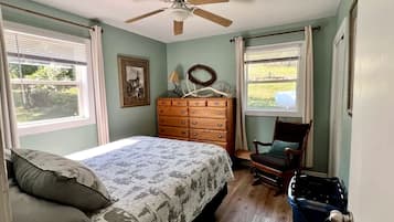Un dormitorio con cama, cómoda, silla y ventilador de techo.
