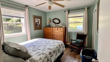 A bedroom with a bed, dresser, chair, and a ceiling fan.