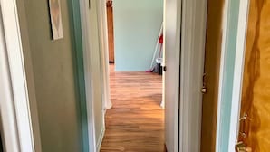 A hallway with wooden flooring, white doors, and light blue walls.