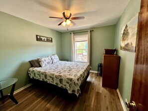 A bedroom with a bed, a ceiling fan, a window, and a door. - Chic Cabin with Lake Views from the Deck in South Dakota (Hot Springs)