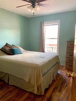 A bedroom with a bed, a dresser, a ceiling fan, and a window with curtains. - Chic Cabin with Lake Views from the Deck in South Dakota (Hot Springs)