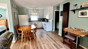 Un espacio habitable compacto con comedor, kitchenette y una pequeña zona de estar.