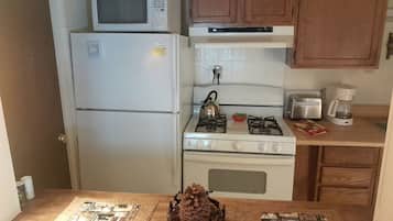 A compact kitchen with a refrigerator, microwave, stove, and a toaster.
