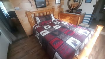 Un lit en bois avec une courtepointe, une commode en bois, un miroir et un tableau encadré accroché au mur.