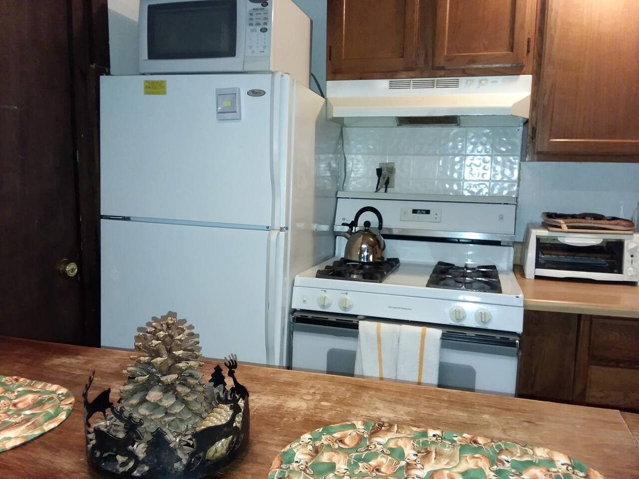 A kitchen with a refrigerator, stove, microwave, and a toaster.