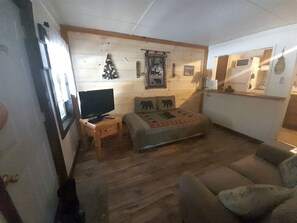 Ein gemütliches Zimmer mit Holzboden, einem Bett mit einer Decke mit Bärenmotiv, einem Fernseher auf einem Nachttisch aus Holz und einer Wanddekoration.