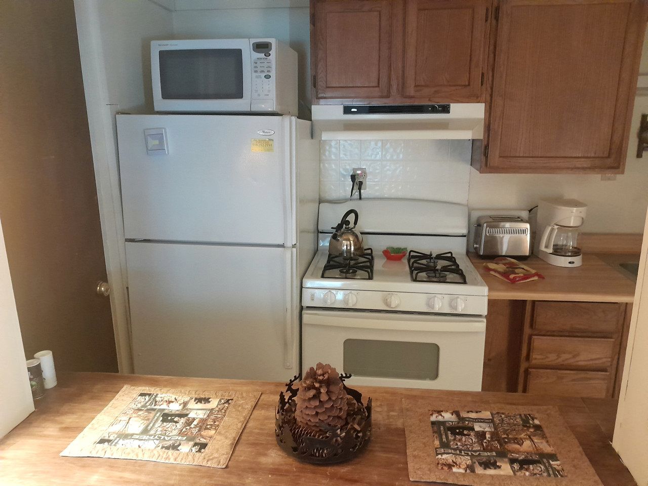 Eine kleine Küche mit Kühlschrank, Mikrowelle, Herd und Toaster.