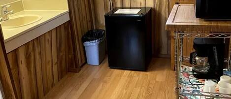 Een kleine keuken met houten wanden, een gootsteen, een magnetron en een koffieapparaat.