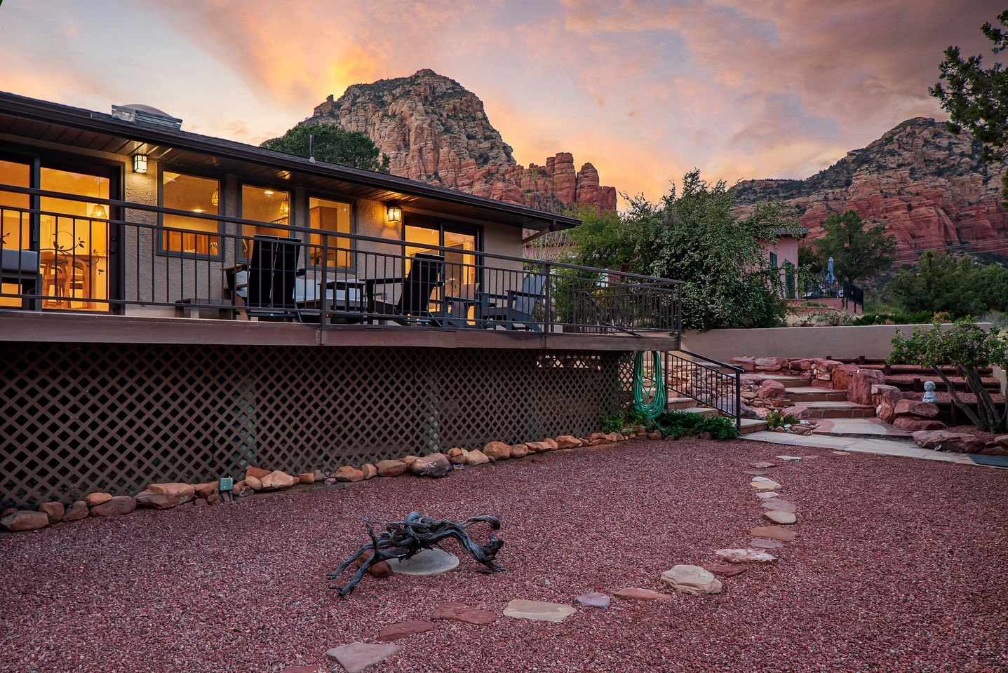 Una casa moderna con un patio, vistas a formaciones rocosas rojas y una zona de estar cubierta al aire libre.