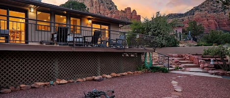 Una casa moderna con un patio, vistas a formaciones rocosas rojas y una zona de estar cubierta al aire libre.