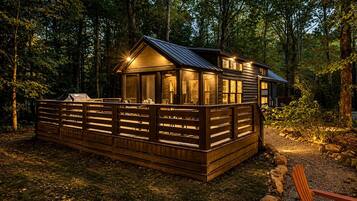 A cabin with a deck, surrounded by trees.