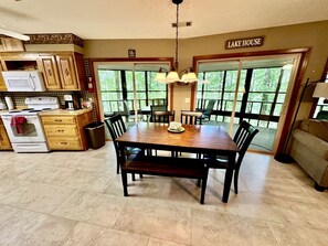 Una cocina con armarios de madera, una mesa de comedor con sillas, una estufa y un microondas.