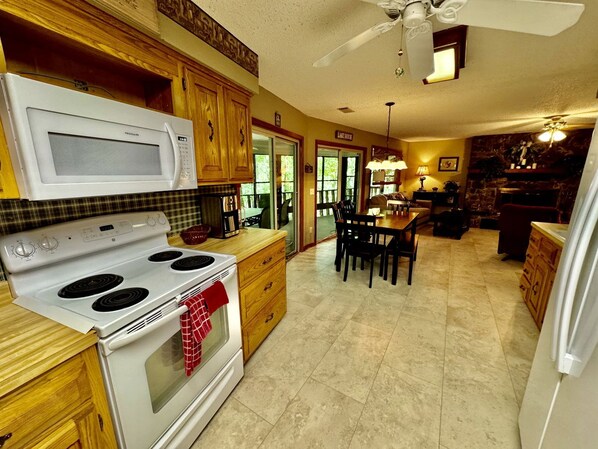 Una cocina con estufa, microondas y armarios de madera.