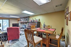 A dining area with a stone fireplace, wooden chairs, and a television. - Waterfront Cabin Ideal for Families and Outdoor Adventures in Arkansas (Fairfield Bay)
