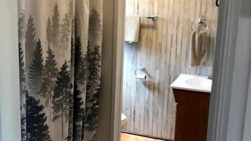 A bathroom with a wooden floor, a white sink, and a towel rack.