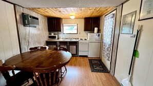 A compact kitchen with a dining table, cabinets, and a microwave.