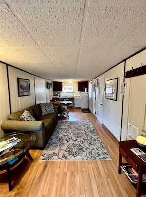 A compact living space with a sofa, coffee table, rug, kitchenette, and a dining area. - Unique Cabin with Deck Great for Families in South Dakota (Hot Springs)