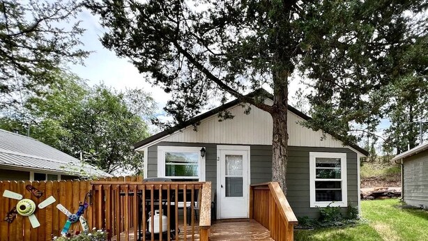 A small house with a wooden deck, a front door, and a window.