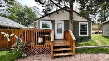 A small house with a wooden deck, a front door, and a window.