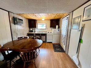 A compact kitchen with a dining table, cabinets, and a microwave.