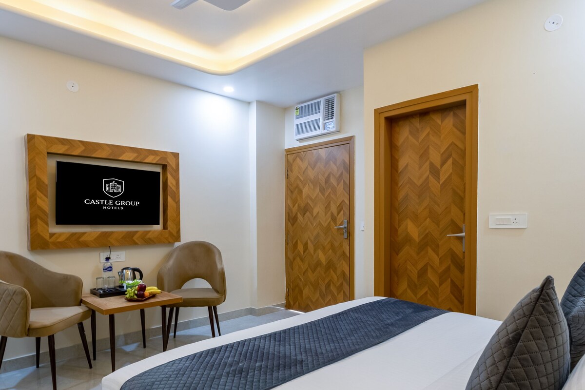 A hotel room with a bed, a desk with a chair, a television, and a ceiling fan.