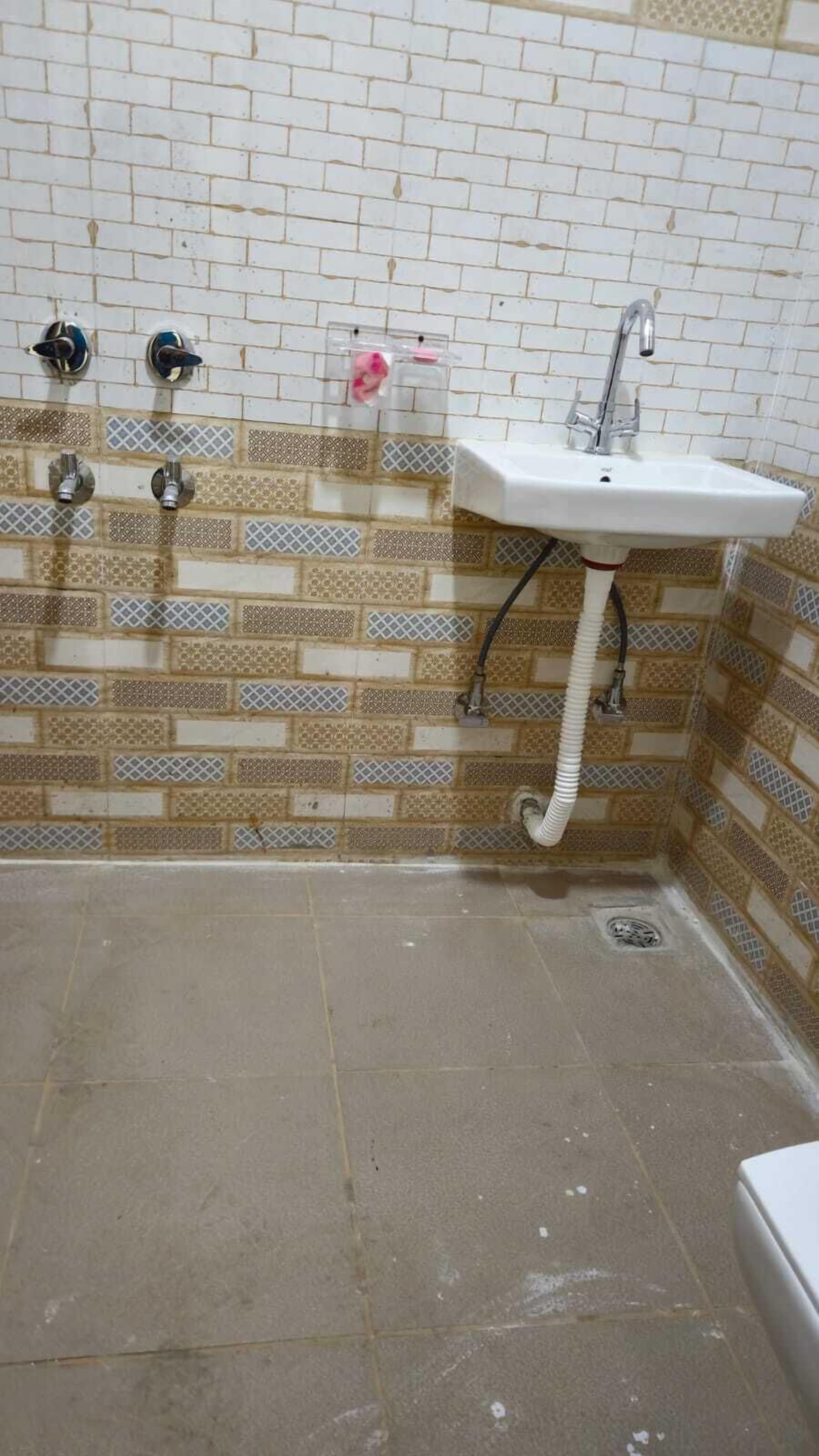 A bathroom with a white sink, two faucets, and patterned tiles on the walls.