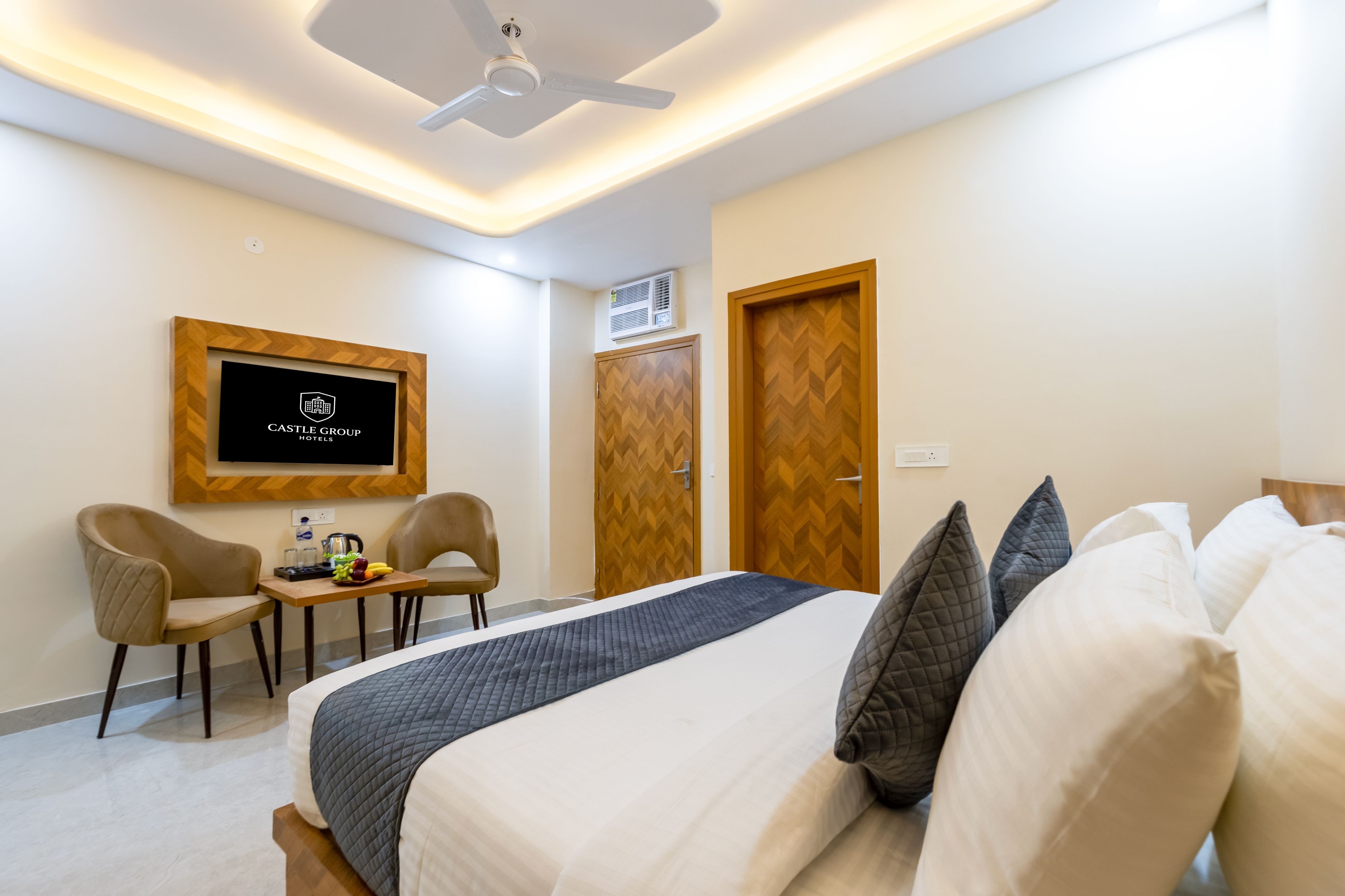 A hotel room with a bed, a desk with chairs, a television, and a wardrobe.