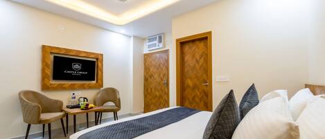 A hotel room with a bed, a desk with chairs, a television, and a wardrobe.