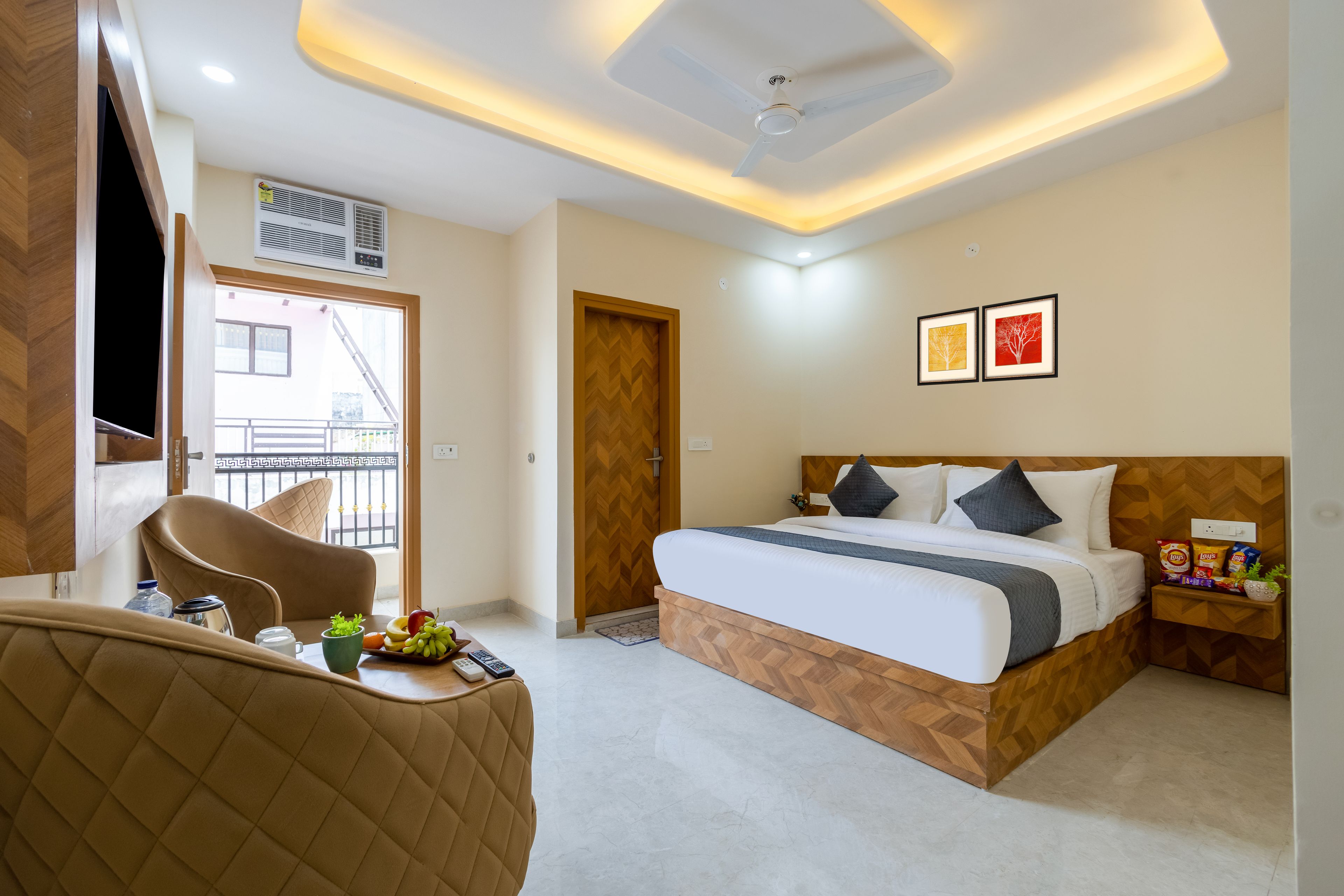 Quarto de hotel com cama, área de estar com uma cadeira, uma pequena mesa com petiscos e vista para o exterior.
