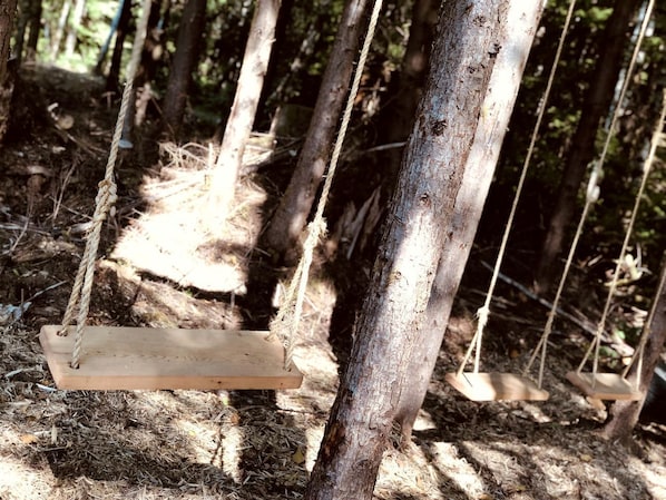 A wooden swing suspended by ropes in a forested area. - Off-Grid Log Cabin near Olympic National Park, Perfect for a Weekend of Hiking in Temperate Rainforests (Forks)
