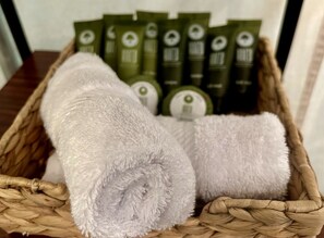 A woven basket containing rolled towels and green bottles.